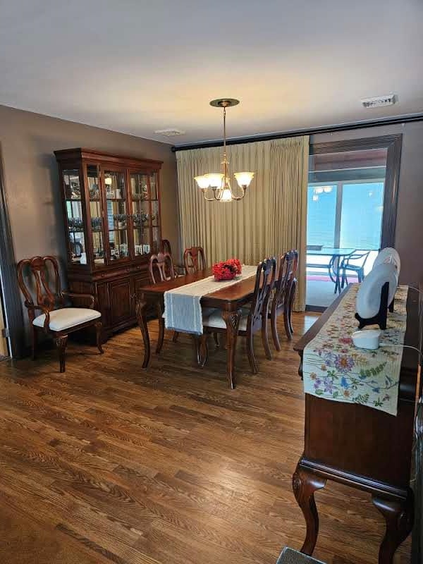 dining area with dark hardwood / wood-style flooring and an inviting chandelier