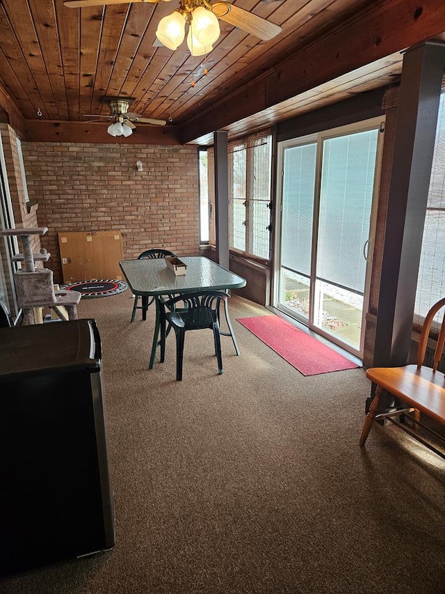 recreation room featuring ceiling fan, plenty of natural light, brick wall, and wood ceiling