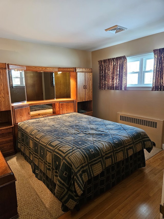 bedroom with dark wood-type flooring and radiator