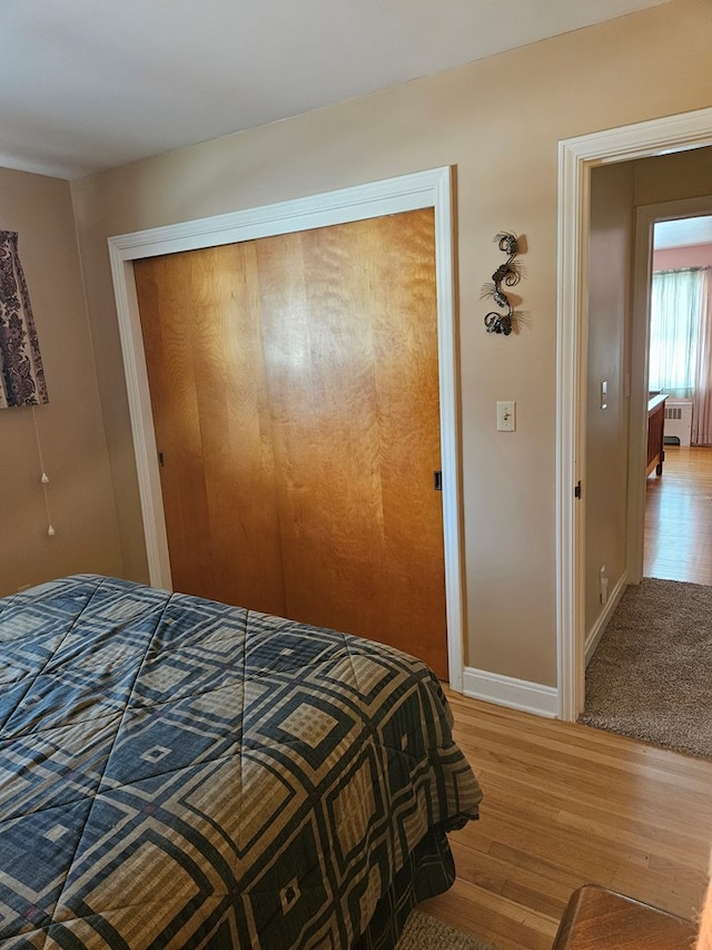 bedroom featuring a closet, radiator heating unit, and light hardwood / wood-style flooring