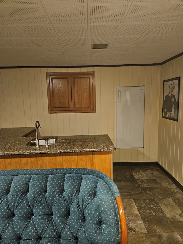 kitchen with dark stone counters, wooden walls, and sink