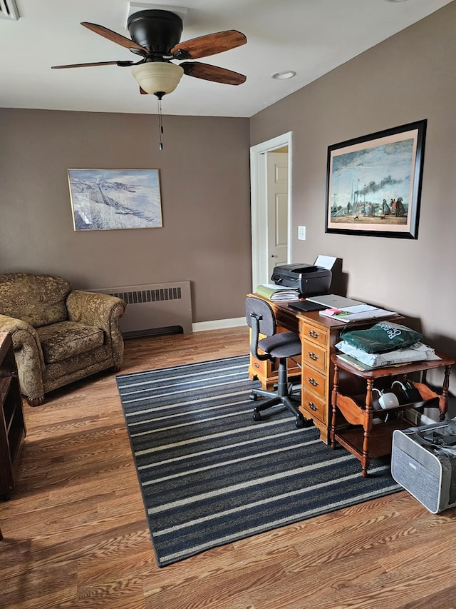 office area featuring ceiling fan, hardwood / wood-style floors, and radiator heating unit