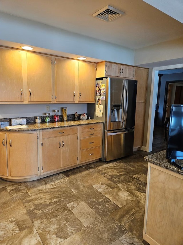 kitchen with stainless steel fridge and dark stone countertops