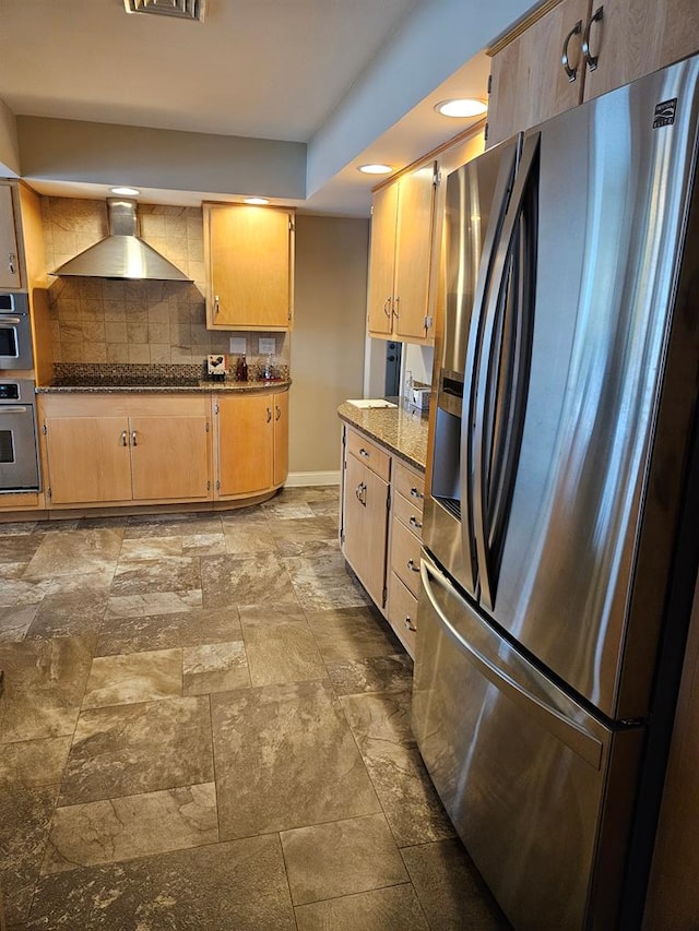 kitchen featuring stainless steel refrigerator with ice dispenser, backsplash, dark stone countertops, wall chimney exhaust hood, and black cooktop