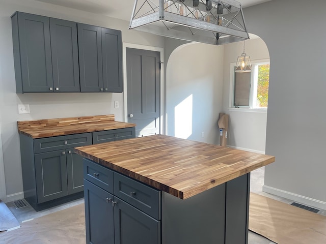 kitchen featuring gray cabinetry, wood counters, pendant lighting, and a kitchen island