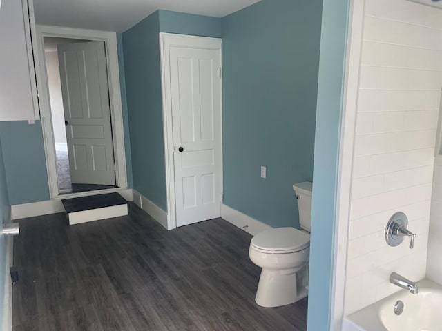 bathroom with hardwood / wood-style flooring, toilet, and tub / shower combination