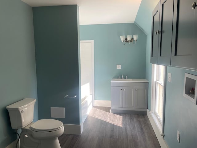 bathroom featuring a tub to relax in, vanity, wood-type flooring, toilet, and lofted ceiling