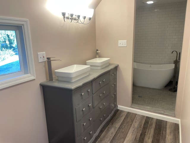 bathroom with hardwood / wood-style flooring, vanity, and a tub