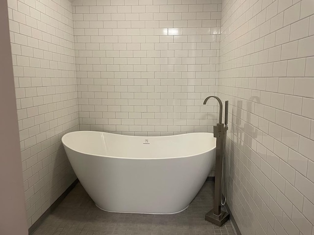 bathroom featuring tile patterned floors, a bath, and tile walls