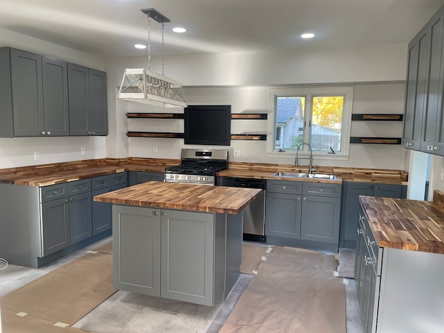 kitchen with sink, stainless steel appliances, wooden counters, gray cabinets, and a kitchen island