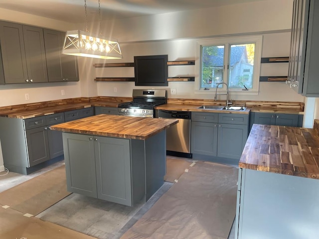 kitchen featuring stainless steel appliances, sink, pendant lighting, a center island, and butcher block counters