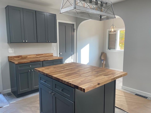 kitchen featuring pendant lighting, gray cabinets, and wooden counters