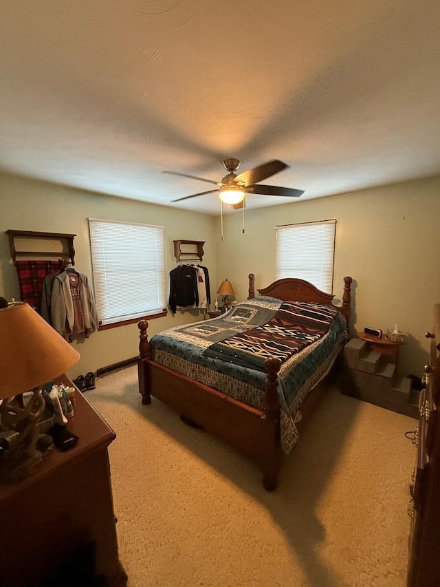 bedroom with ceiling fan, light carpet, and a textured ceiling