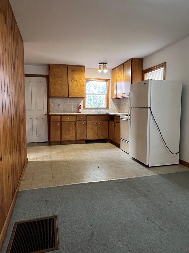 kitchen with decorative backsplash, white refrigerator, range, and sink