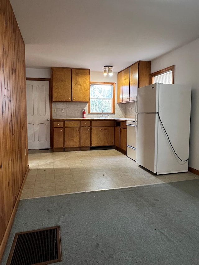 kitchen with sink, backsplash, stove, and white fridge