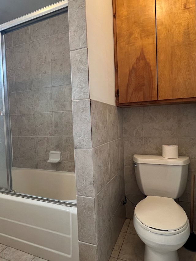 bathroom with toilet, bath / shower combo with glass door, and tile patterned floors