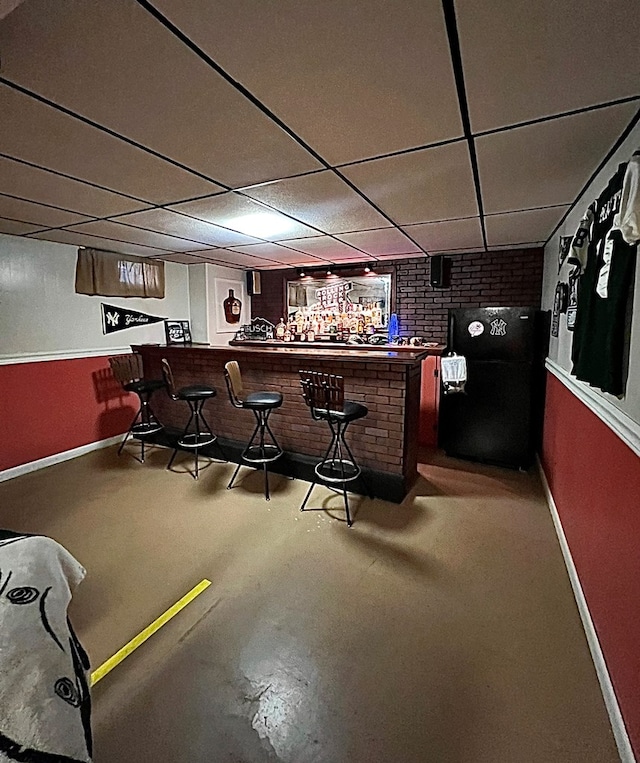 bar with black fridge and a drop ceiling