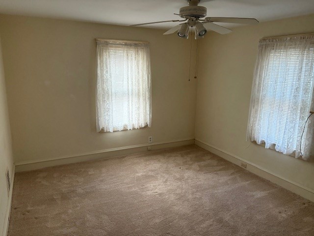 spare room with ceiling fan and light colored carpet