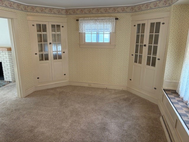 carpeted spare room featuring a brick fireplace, french doors, and crown molding