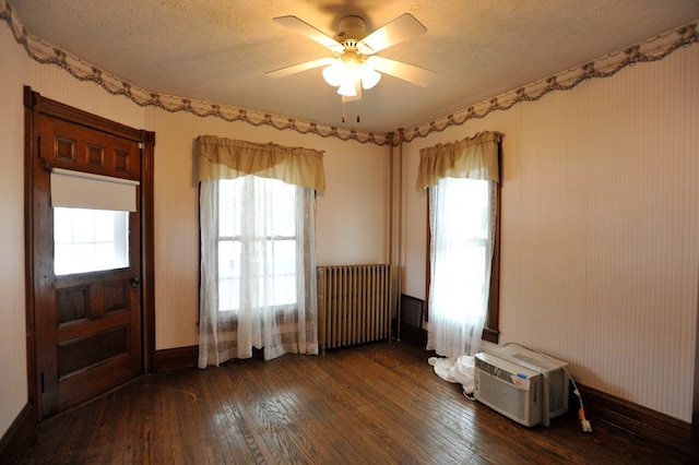 unfurnished room featuring plenty of natural light, radiator, dark wood-type flooring, and ceiling fan