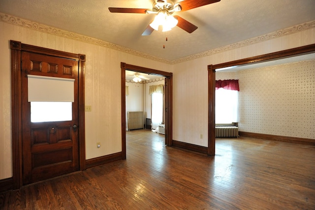 unfurnished room with dark hardwood / wood-style flooring, ceiling fan, radiator heating unit, and a textured ceiling