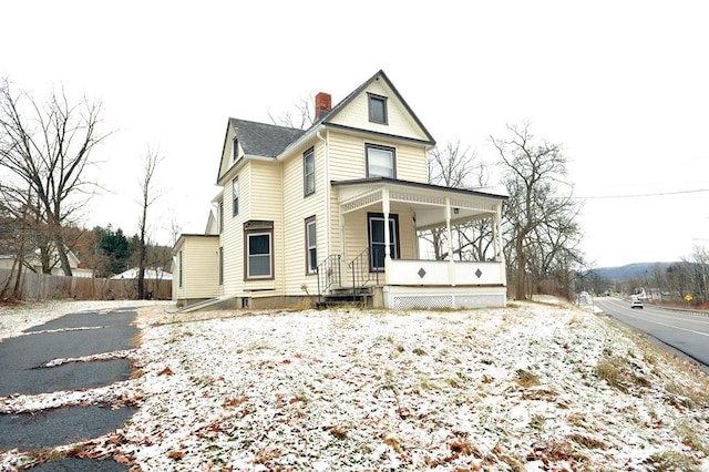 snow covered rear of property with a porch