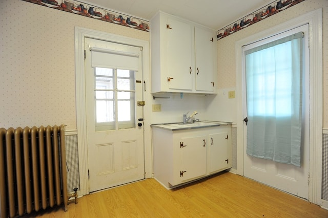 doorway featuring radiator heating unit, sink, and light wood-type flooring