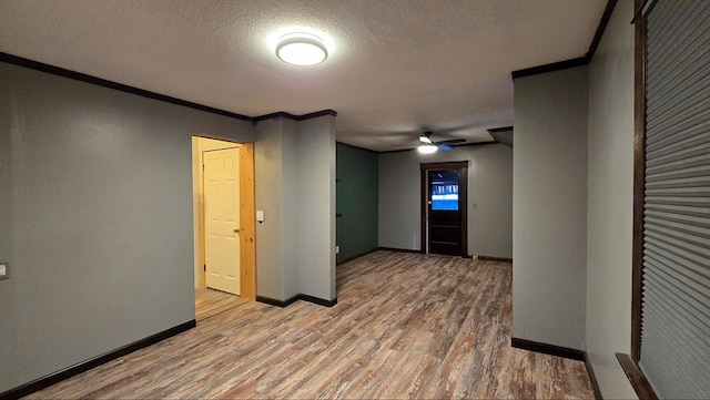 empty room with ceiling fan, ornamental molding, a textured ceiling, and light wood-type flooring