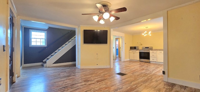 unfurnished living room featuring ceiling fan with notable chandelier, light hardwood / wood-style flooring, and ornamental molding