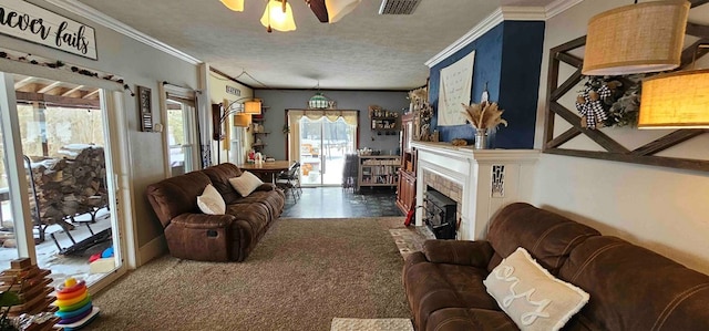 carpeted living room with a textured ceiling, ceiling fan, crown molding, and a fireplace