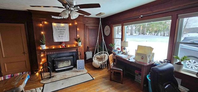 living area with a fireplace, wood walls, ceiling fan, and light hardwood / wood-style flooring