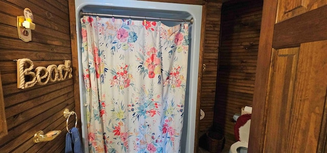 bathroom with wooden walls and a shower with curtain