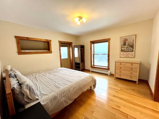 bedroom with light wood-type flooring and a baseboard heating unit