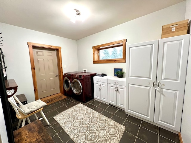 washroom with cabinets, dark tile patterned floors, and washing machine and clothes dryer