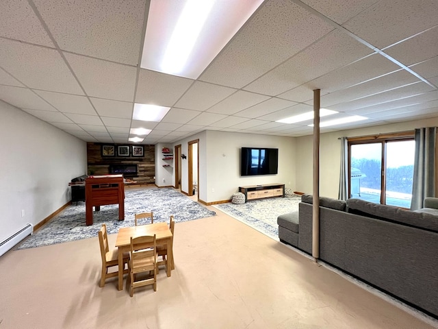 recreation room with baseboard heating, a fireplace, and a drop ceiling