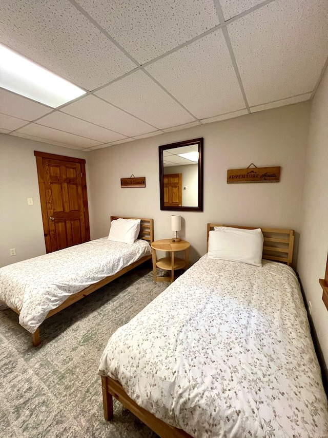 bedroom with carpet floors and a paneled ceiling