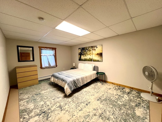 carpeted bedroom with baseboard heating and a paneled ceiling