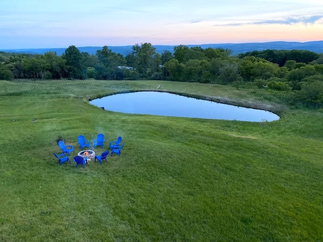 exterior space featuring a yard, a water view, and an outdoor fire pit