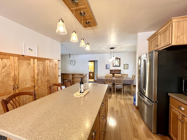 kitchen featuring decorative light fixtures, stainless steel fridge, and light wood-type flooring