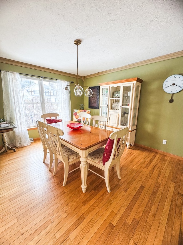 dining room featuring crown molding, light hardwood / wood-style flooring, and a textured ceiling