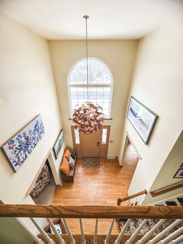 foyer with a towering ceiling, hardwood / wood-style floors, and an inviting chandelier