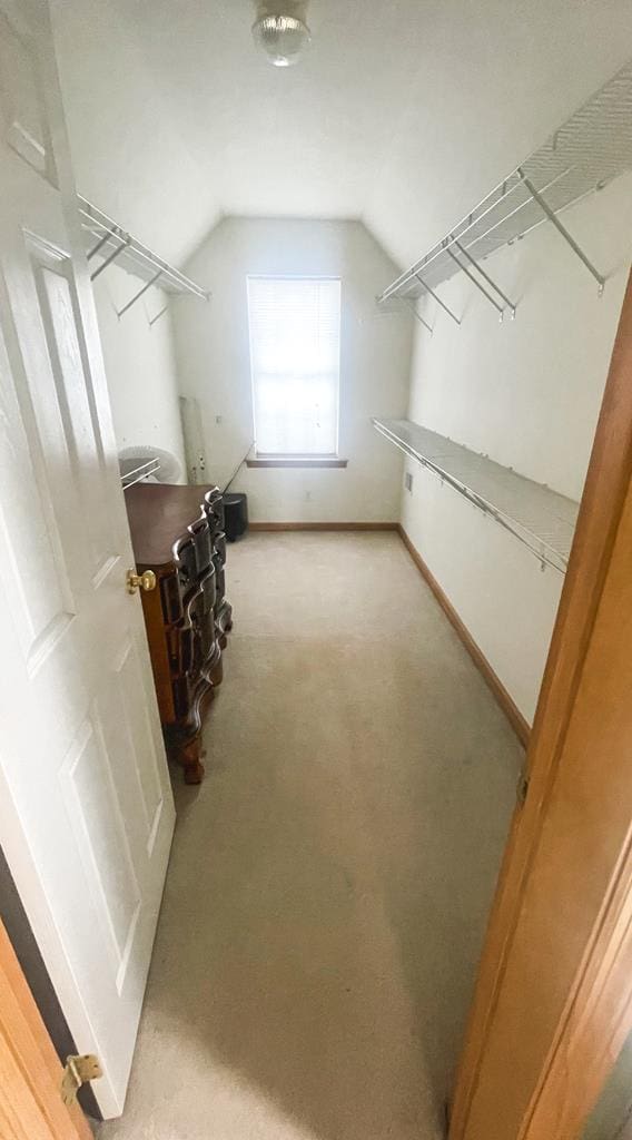 spacious closet with lofted ceiling and light carpet