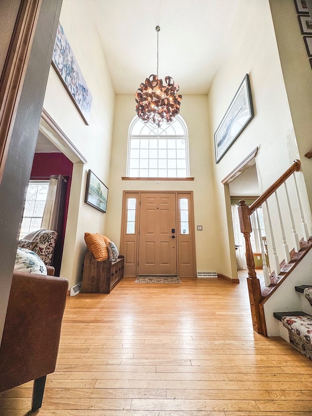 foyer with an inviting chandelier, a high ceiling, and light wood-type flooring