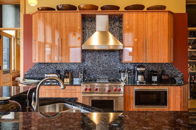 kitchen featuring backsplash, designer range, dark stone counters, black microwave, and wall chimney exhaust hood