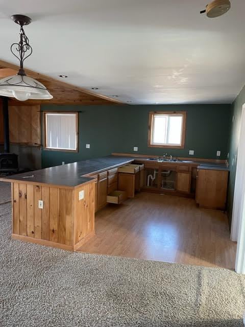 kitchen featuring decorative light fixtures, kitchen peninsula, a wood stove, and light hardwood / wood-style flooring