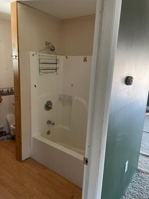 bathroom with shower / bathtub combination, wood-type flooring, and toilet