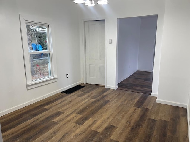 unfurnished room with dark wood-type flooring and an inviting chandelier