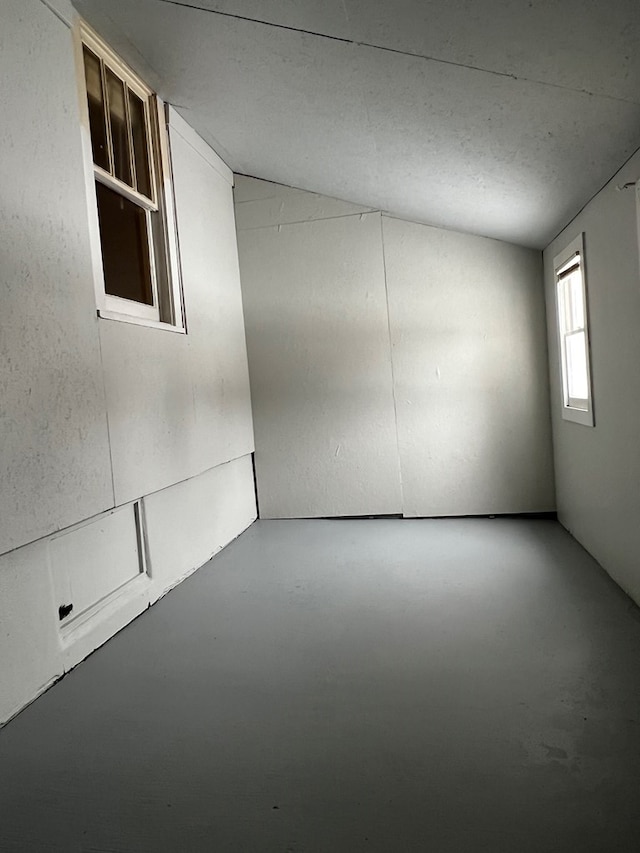 empty room featuring concrete floors and vaulted ceiling