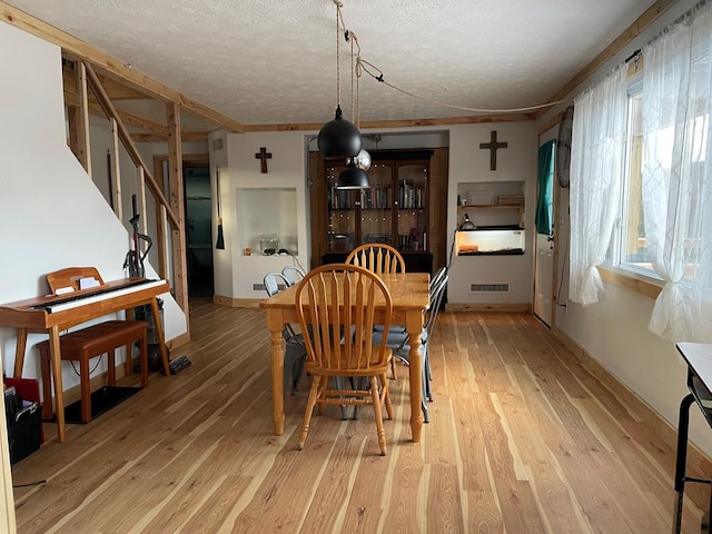 dining area with light hardwood / wood-style flooring and a textured ceiling