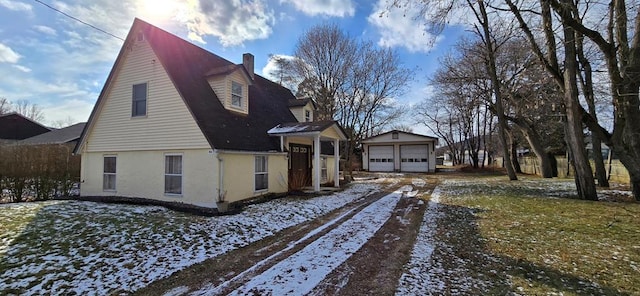 snow covered property featuring a garage and an outdoor structure